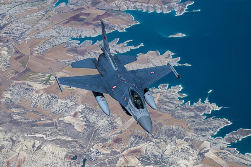 Турецький винищувач F-16 летить над скелястим ландшафтом і синьою водоймою